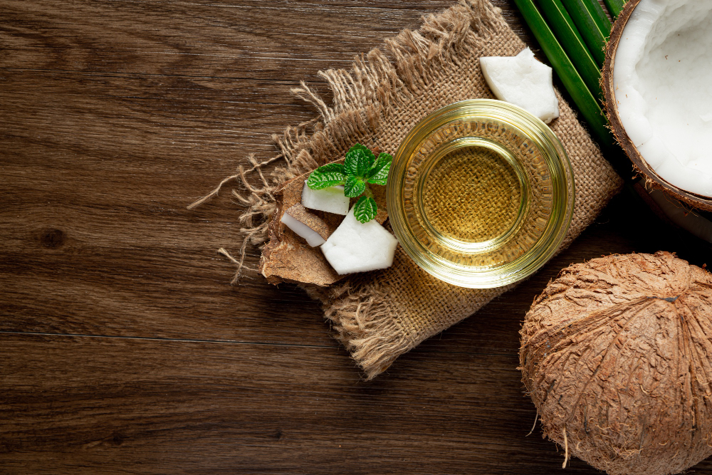 shelled coconut and natural hair oil, coconut oil in a bowl placed on a wooden board
